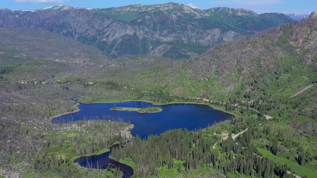 Drone flies forward, mountain lake and winding river in Katon Karagay national park Altai East Kazakhstan revealing vast wilderness valley with forest, alpine landscape ideal for travel, nature themes