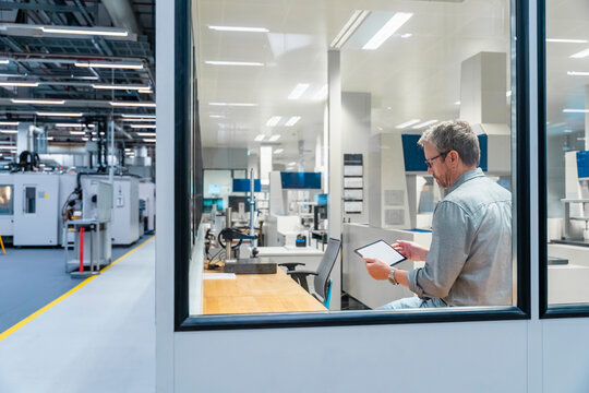 Engineer in control room using tablet at modern manufacturing facility