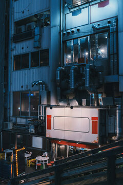 Urban night scene with outdoor restaurant seating and pipes in Osaka