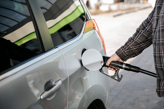 Driver refilling silver car with diesel at gas station