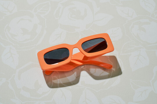 Orange retro rectangular sunglasses on floral background