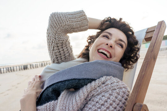 Cheerful woman relaxing on deck chair at beach