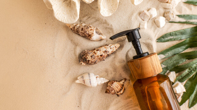 Natural skincare product with seashells and palm leaf on sandy beach background