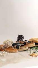 Obraz premium Stylish summer sandals and straw hat arranged on a sandy beach with seashells