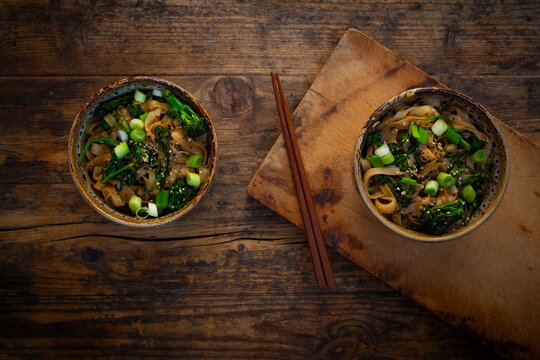 Miso rice noodles with baby broccoli and scallions on wooden table