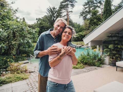 Couple embracing outdoors at home by the pool on summer vacation