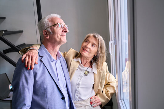 Loving couple looking out the window indoors