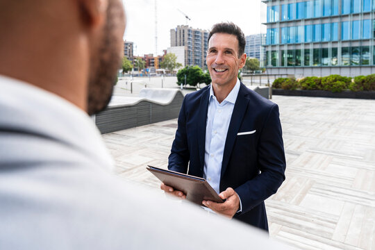 Smiling businessman talking with coworker in financial district
