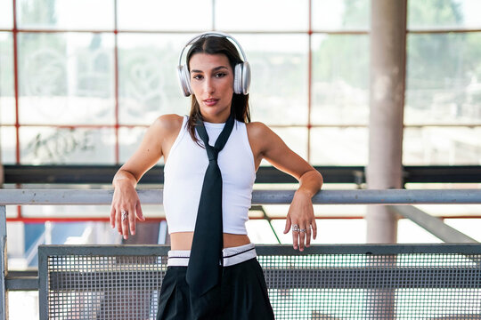 Urban fashion model listening to music with headphones in the city