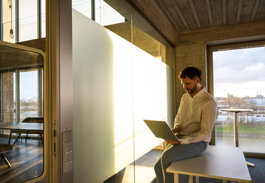 Businessman working on laptop in modern office at evening