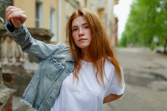 Portrait of model with red hair and denim jacket outdoors in summer