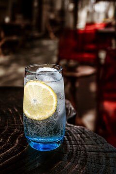 Glass of cold sparkling water with lemon on a terrace table