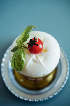 Fresh burrata with tomato and basil on a metal plate