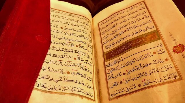 Horizontal slow tilt-up shot of an open ancient Quran. Gradually revealing the beautiful calligraphy and the red leather binding in a cinematic view