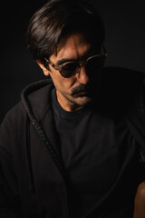 Obraz premium Mysterious man in sunglasses captures underground style in dim setting