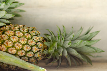 Obraz premium Close up of fresh pineapple showing detailed texture and green leaves. Natural lighting with rustic background for tropical fruit concept.