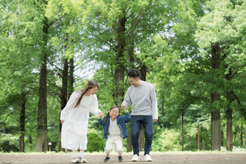 Fototapeta premium 家族、新緑の公園で手を繋ぐ歩く幸せなファミリーライフスタイル 全身
