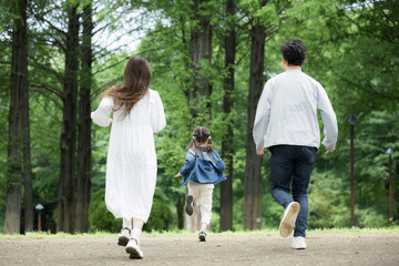 Fototapeta premium 家族、新緑の公園で走る、かけっこする幸せなファミリーライフスタイル 全身の顔無しの後ろ姿