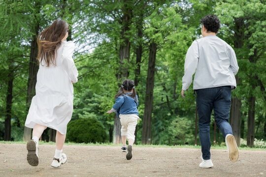 家族、新緑の公園で走る、かけっこする幸せなファミリーライフスタイル　全身の顔無しの後ろ姿