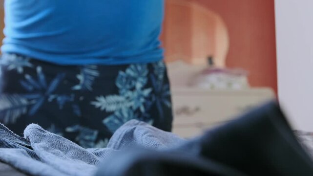 Close-up of male hands folding garments and arranging clothes neatly for storage. Home organization process, wardrobe management, laundry routine and maintaining order in everyday domestic life.