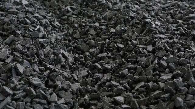 Dense pile of shredded black plastic flakes and chips after industrial shredding process
