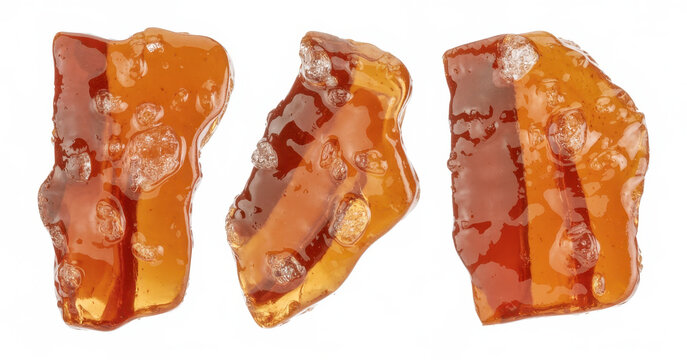 Three pieces of transparent amber resin or hard candy fragments isolated on a white background