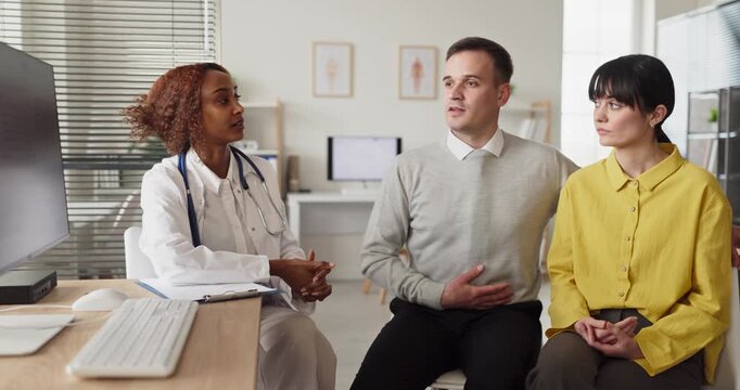 Doctor couple consultation on pregnancy planning. In a healthcare clinic, a physician offers advice on fertility options as the pair considers next steps. Clear reproductive guidance for family.