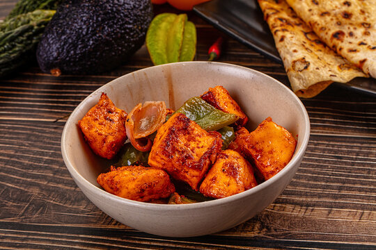 Indian Paneer Tikka Masala inl with Roti bread on a dark wooden table