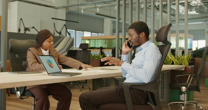 Black project manager negotiating contract on phone in office