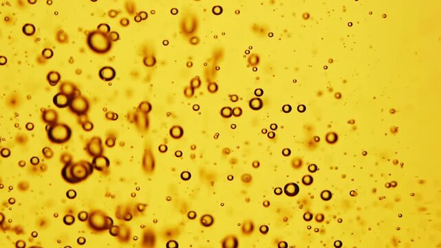 Macro shot of sunflower oil bubbles on golden background, abstract liquid texture, cooking ingredient detail, fluid pattern design.