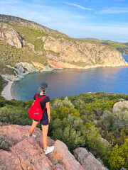 Naklejka premium Woman with backpack standing on a rocks above the sea in Greece 
