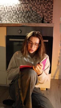 Vertical screen young woman refocuses on studying writing notes in notebook after distraction regaining concentration building discipline quiet home space productive moment