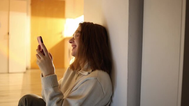 Young woman laughing at phone avoiding responsibilities choosing endless content over tasks light mood hides procrastination habit quiet home space and wasted time