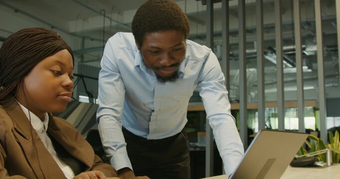 Experienced coach helping colleague using touchscreen in workspace