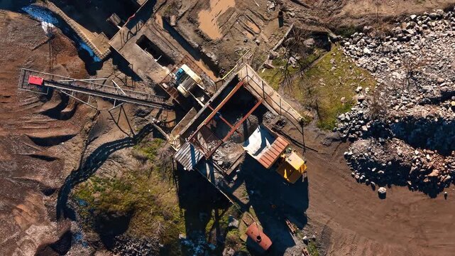 Top view of crushing machinery and aggregate processing unit. Detailed aerial view of heavy machinery and conveyor systems used for crushing and screening rocks into gravel.