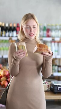 Girl pick up cheese in store. Customer consider make choice cheese, compare varieties products. Client hesitate before buying, choose cheese