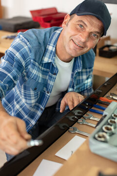 man in workshop selecting tool from drawer in cabinet