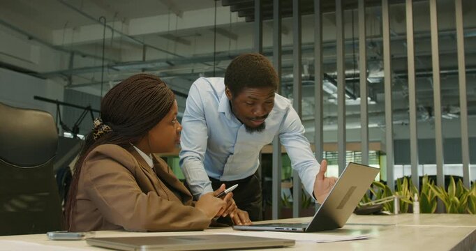 Manager assisting colleague with device issues amidst office greenery