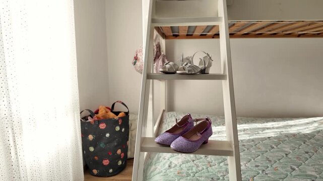 Girls glitter purple dress shoes and silver sandals displayed on white wooden ladder shelf in cozy children bedroom