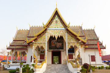 Obraz premium Traditional Thai temple building featuring exquisite architecture and naga sculptures under a bright evening sky.