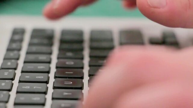 Professional Businessman Working Remotely and Typing on a Sleek Laptop Keyboard with Shallow Depth of Field
