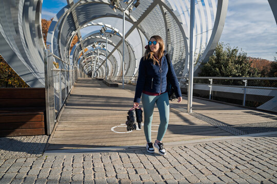 Woman walking on modern arganzuela footbridge carrying inline skates