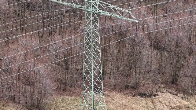 Inspection drone captures high voltage tower on hillside with forest in early spring using close range and distant perspectives