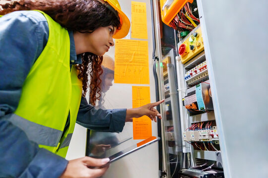 Engineer examining fuse box holding tablet PC