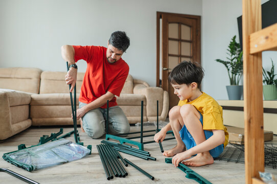 Father and son assembling furniture together on living room floor