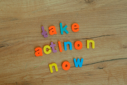 Take action now written with colorful plastic letters on wood