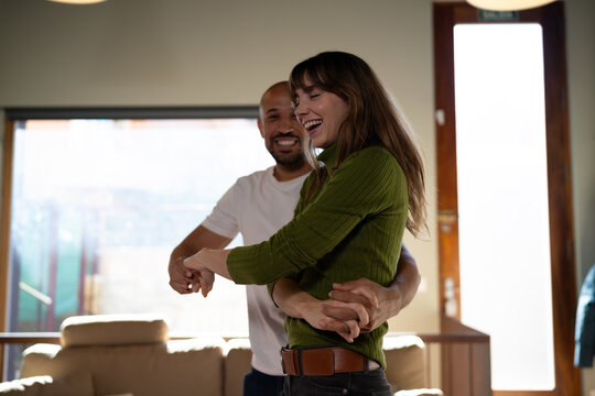 Couple dancing and laughing together in a bright living room