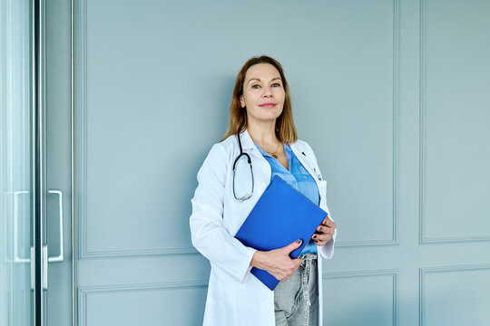 Confident doctor with stethoscope holding folder at the clinic