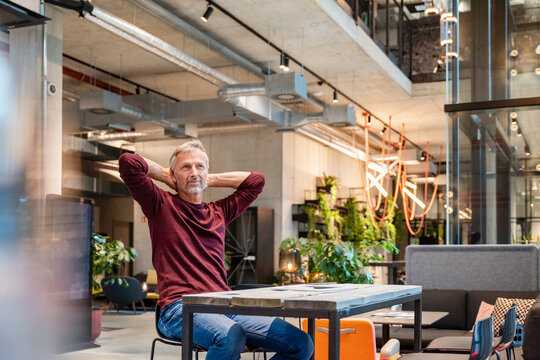 Relaxed businessman in modern open plan office workspace