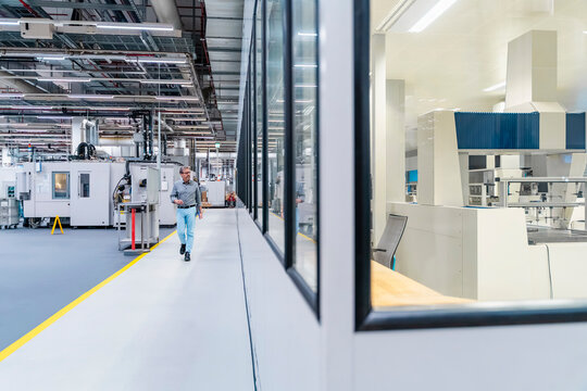 Engineer with tablet in modern production hall with machinery